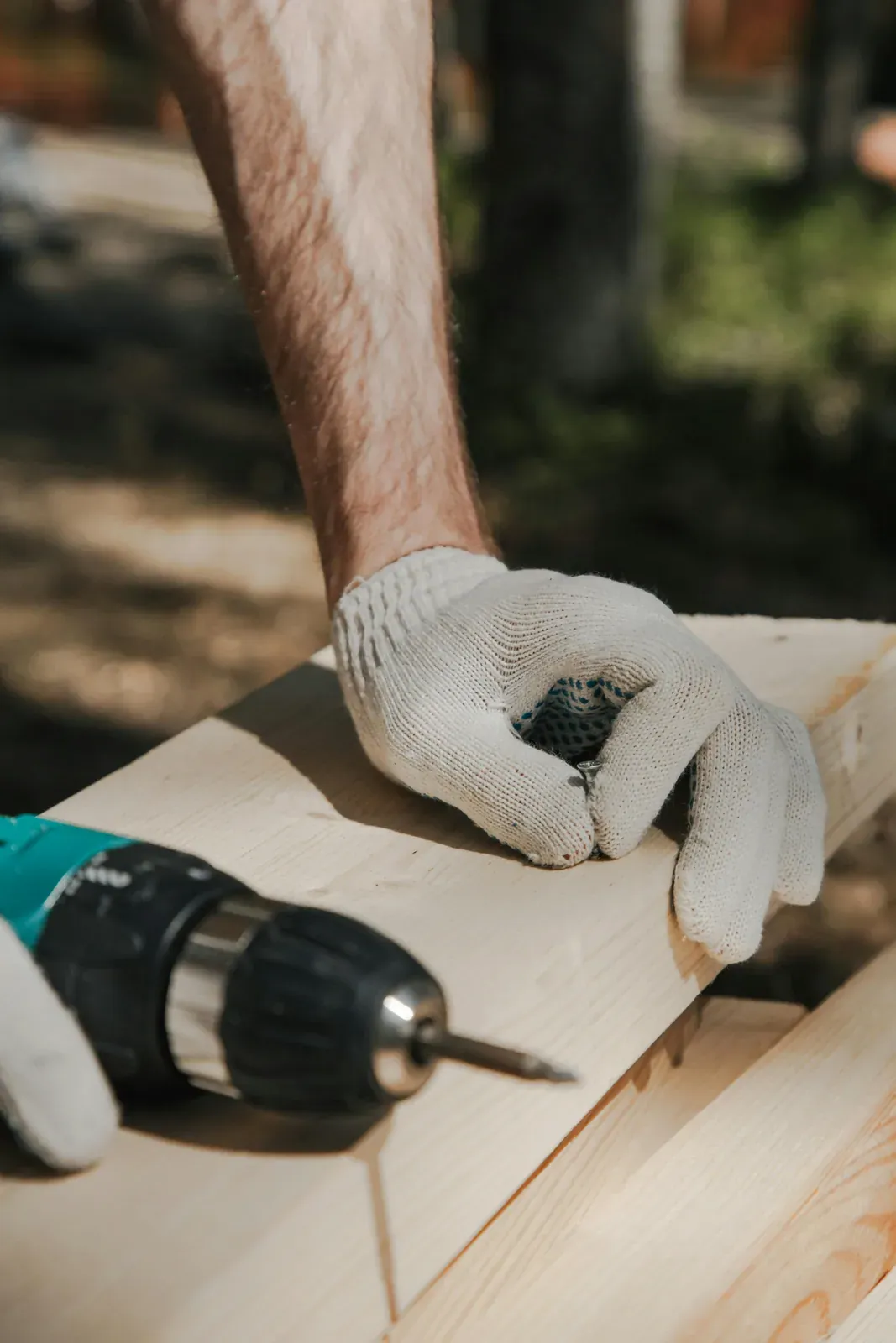 Hand mit Akkuschrauber beim Verschrauben eines Holzbalkens